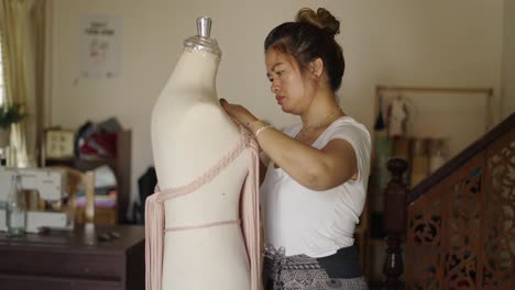 a woman crafting a macrame garment on a mannequin