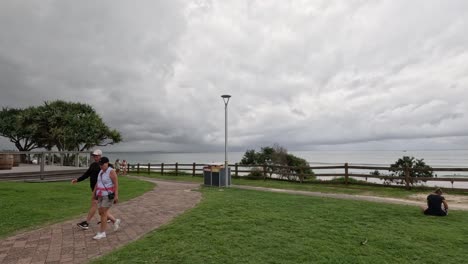 person strolling past a coastal building under cloudy skies