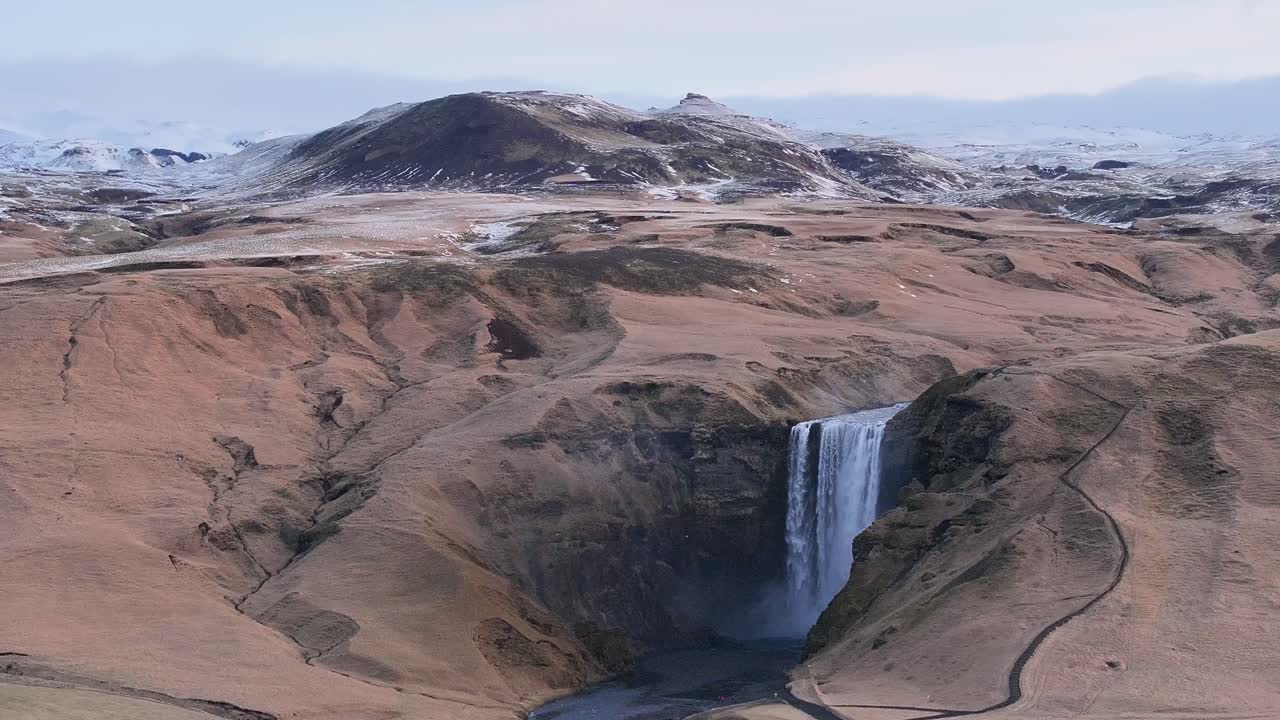 Skógafoss waterfall plunges into a gorge amid thawed terrain near Eyjafjallajökull. Skógar, Iceland