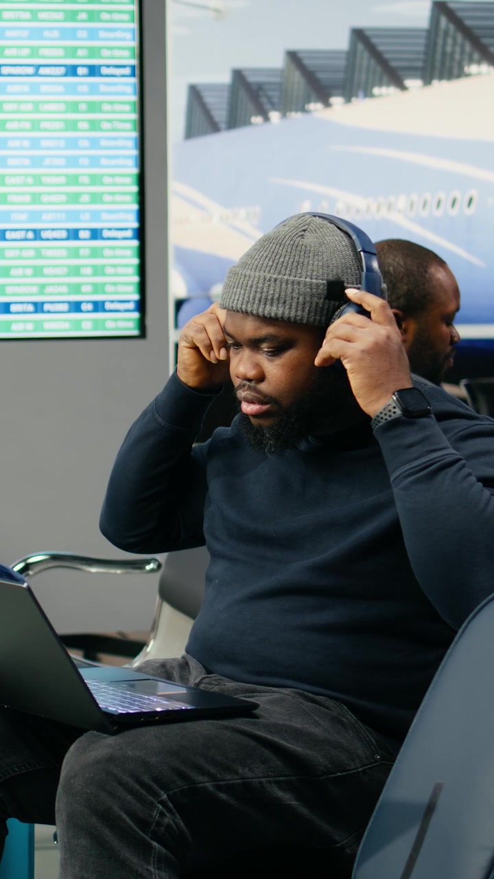 Vertical Video African american worker, using laptop in airport, wearing relaxed outfit
