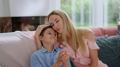 Smiling-mother-and-son-sitting-on-sofa