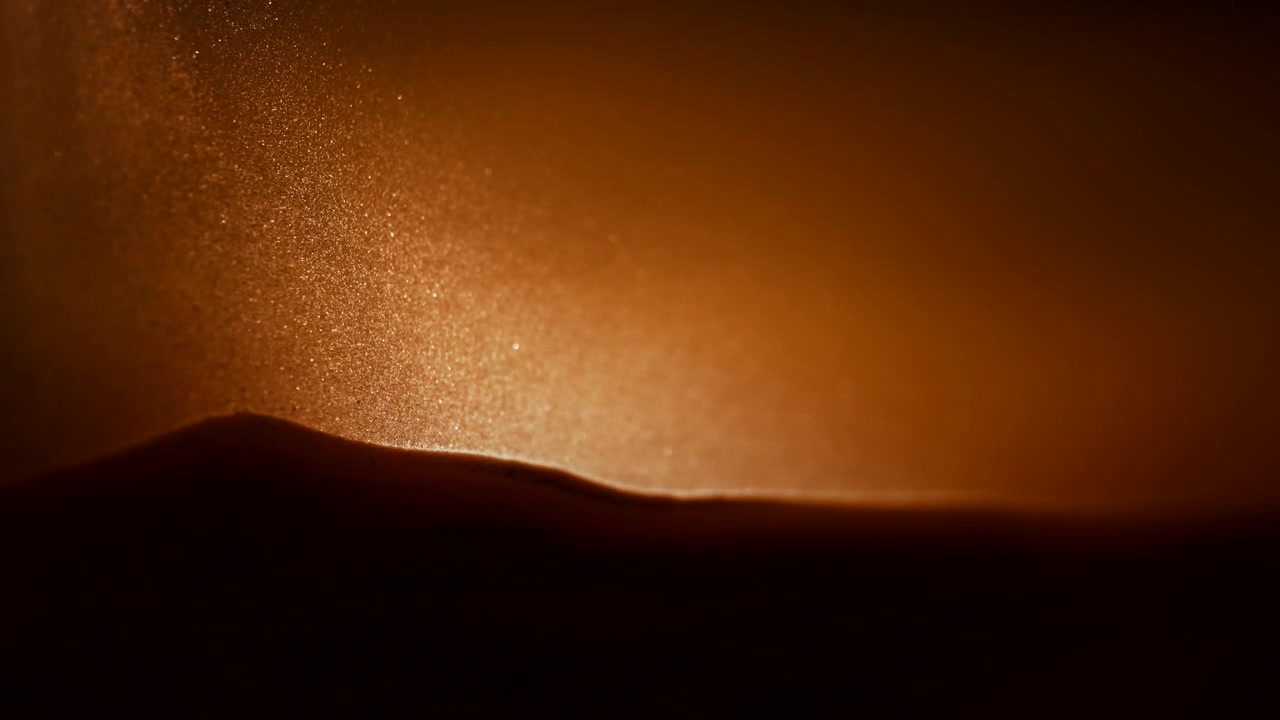Luce che illumina particelle di sabbia che fluttuano al rallentatore.