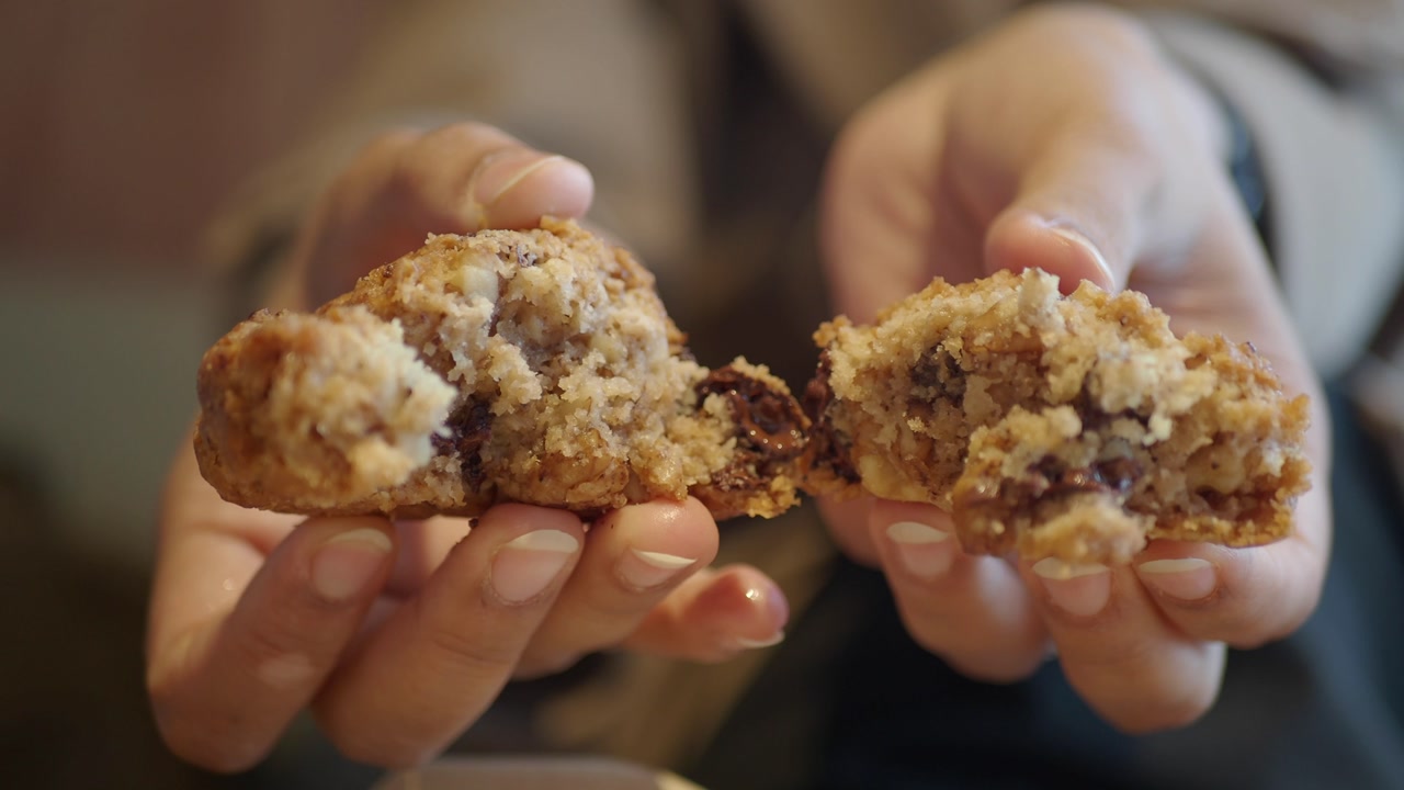 Close-up of Hands Breaking a Warm Chocolate Chip Cookie