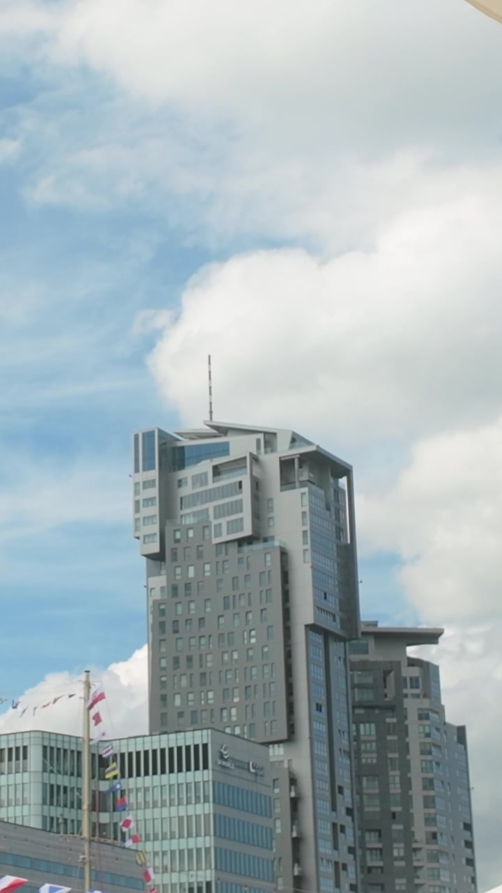 Uma foto em ângulo baixo do icônico edifício Sea Towers em Gdynia, Polônia. Este moderno complexo residencial e de escritórios se destaca contra um céu azul claro com nuvens brancas