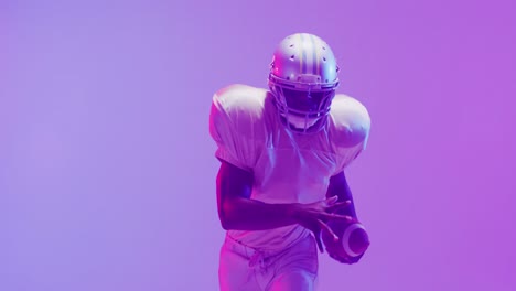 Video-of-african-american-american-football-player-with-ball-over-purple-background