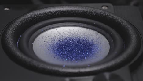 trembling loudspeaker throwing orange dust in the air. super slow motion close-up shot