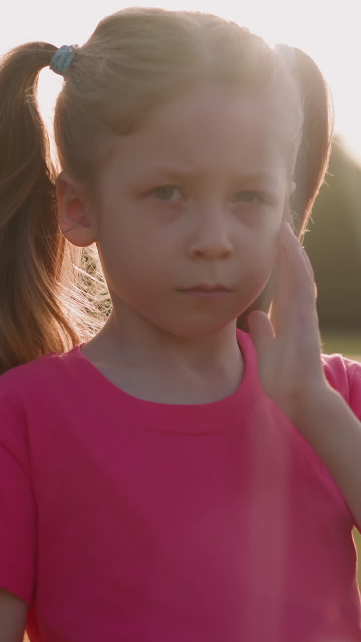 Offended little child closes injured eye standing on meadow closeup slow motion. Children victims and domestic violence. Protection from aggression