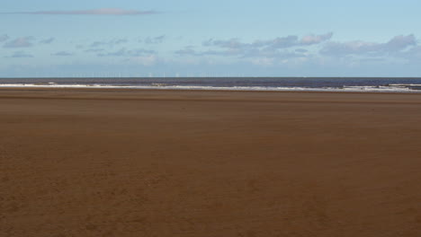 extra wide shot of waves breaking onto a flat sandy beach at saltfleet, louth, lincolnshire