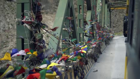 tibetan flags in a bridge over a glacial river - mountain road to indo tibetan border in the himalayas north india