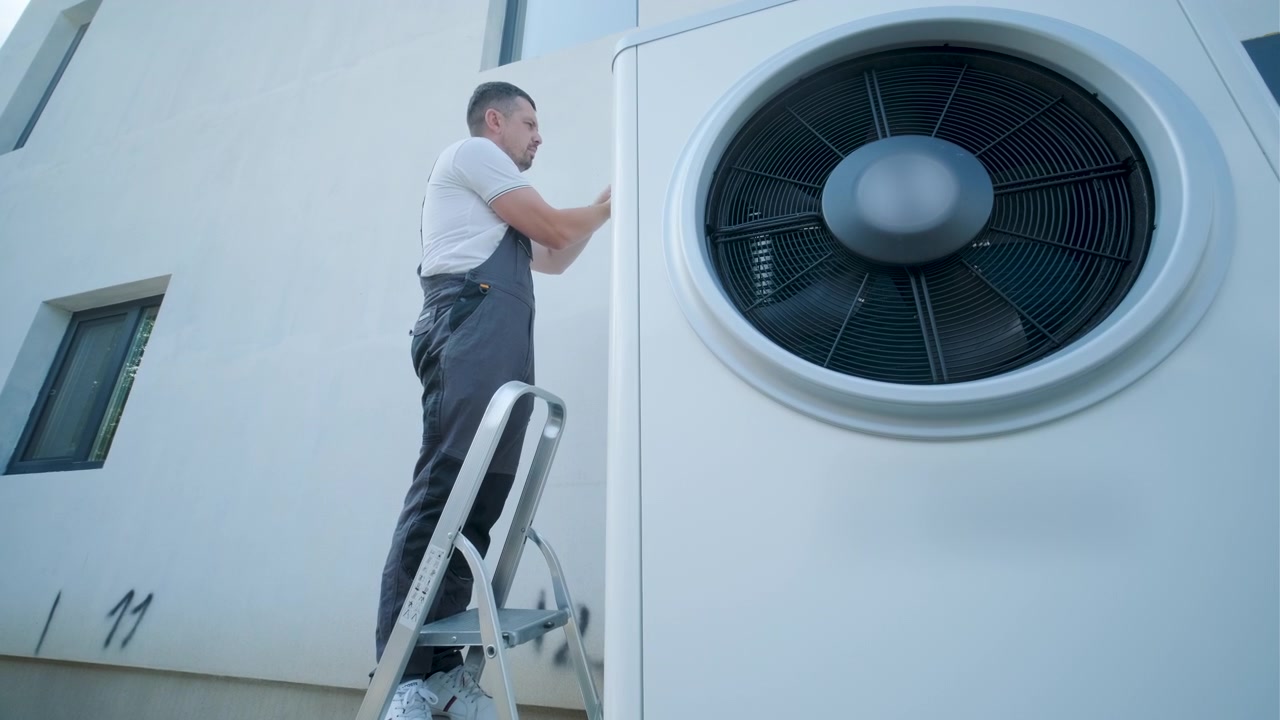 Technicus installeert warmtepompunit aan buitenmuur