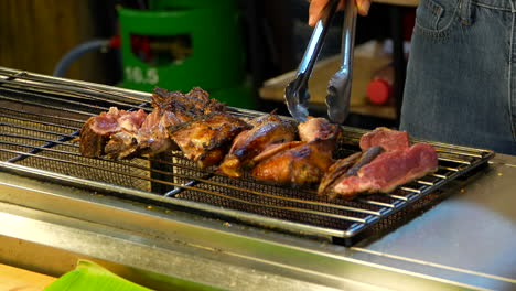 roasting pieces of duck on rustic barbecue in a street stall