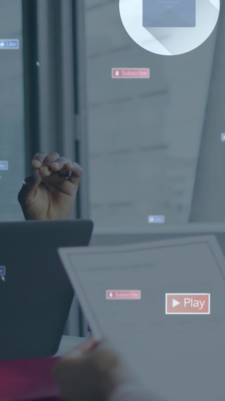 Animation of social media icons floating over two diverse men discussing at office