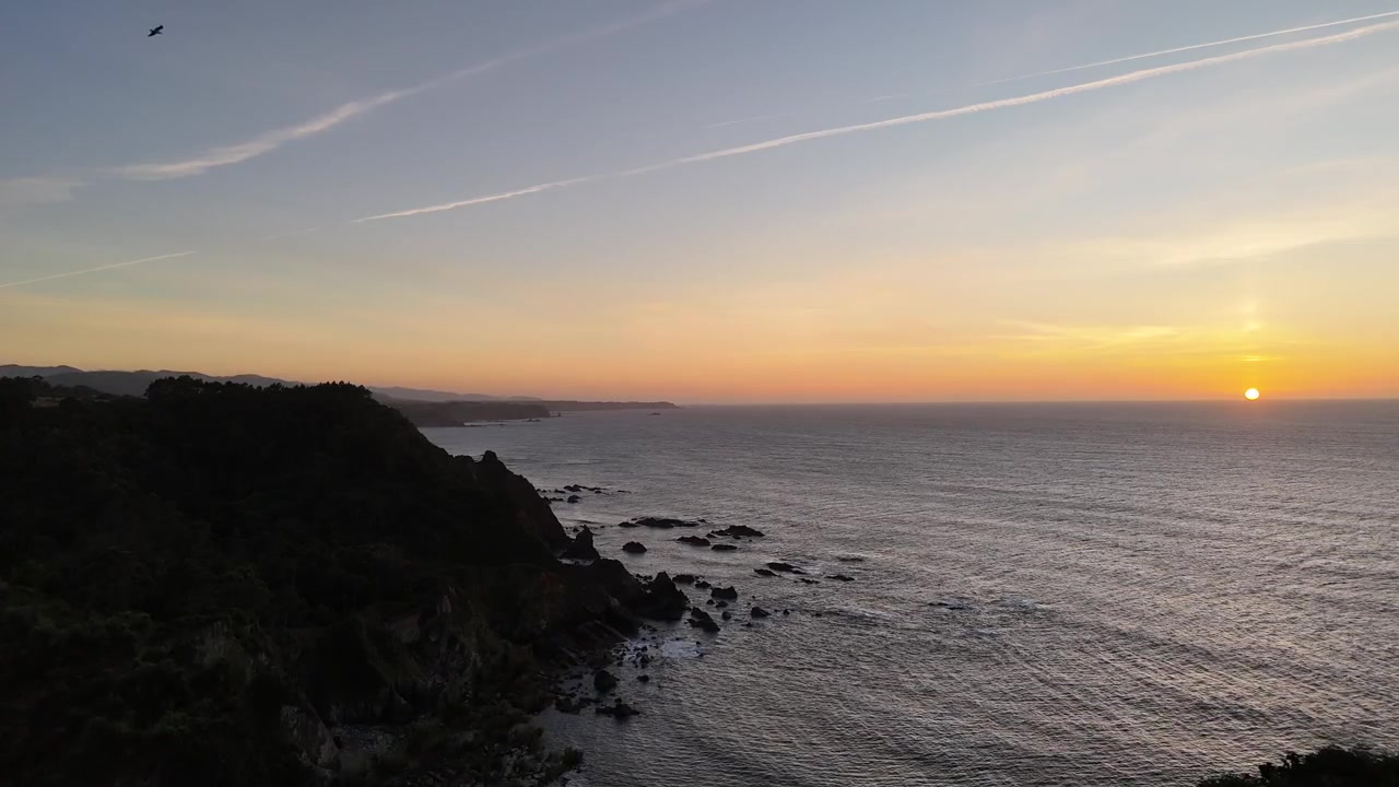 Orange sunset over the Asturias coastline with rocky cliffs and open sea
