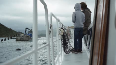 slowmo - kids standing on boat deck and looking at new zealand greenshel mussel farm