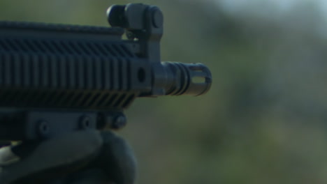 smoke exits a military rifle as it is being shot