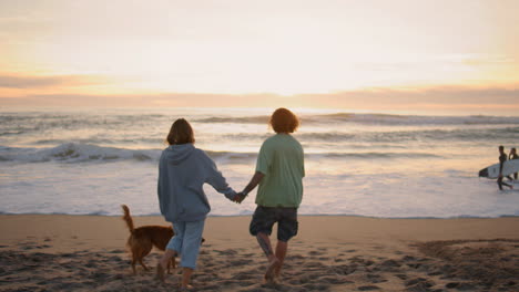 love teenagers running sandy beach evening back view. carefree couple enjoying