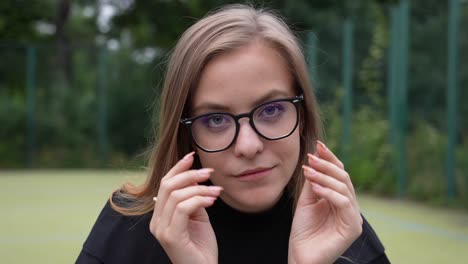 cerca de una joven con gafas y mirando a la cámara con una sonrisa, fotograma completo a cámara lenta