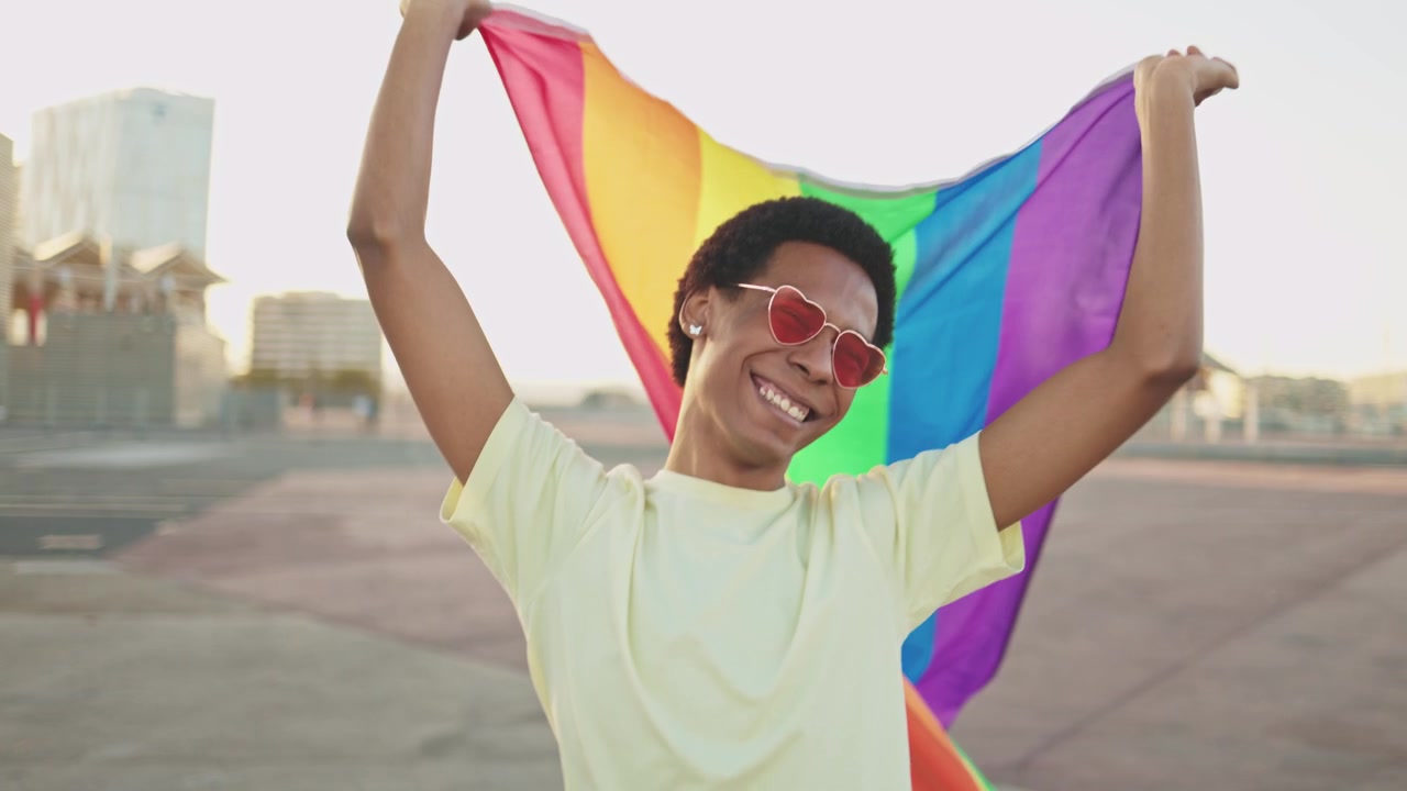 Jovem Feliz Agitando a Bandeira do Orgulho LGBTQ+ Arco-Íris ao Ar Livre