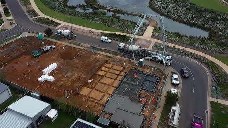 trabajadores de la construcción aérea vertiendo y alisando hormigón nuevo en el sitio de la casa