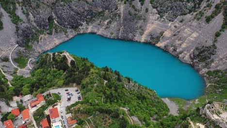 toma de drones del lago azul imotski en un cráter de piedra caliza con un edificio al lado