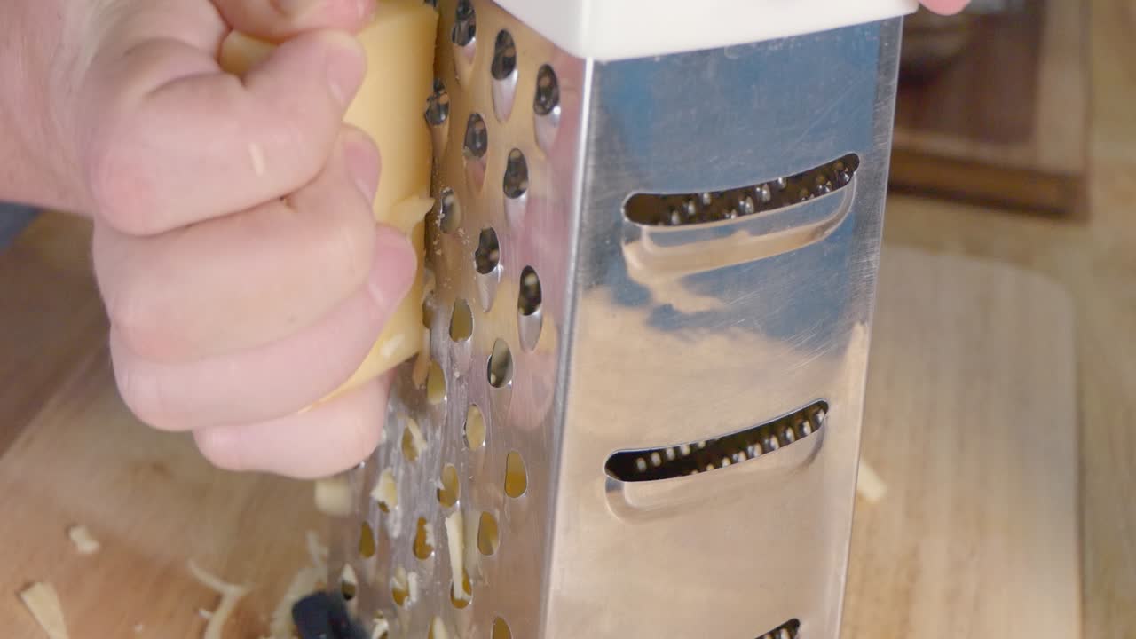 primer plano de rallar queso emmental con un rallador de queso de caja