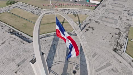 ángulo-Alto-Y-Cámara-Lenta-De-La-Bandera-De-La-República-Dominicana-Ondeando-Sobre-El-Arco-Triunfal-En-La-Plaza-De-La-Bandera,-Santo-Domingo