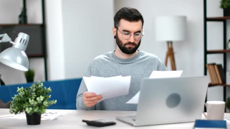 focused man office employee checking paper documents report financial balance bill working at modern desk