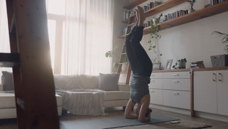 mujer de yoga saludable haciendo ejercicio en casa practicando postura de parada de cabeza apoyada en la sala de estar disfrutando del entrenamiento físico matutino