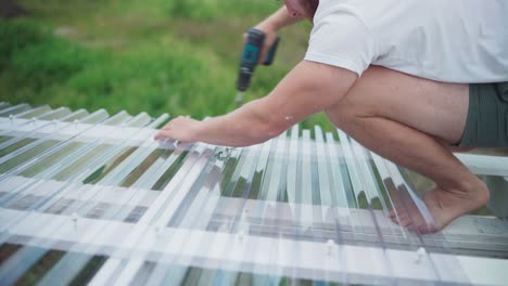 man assembling polycarbonate roof sheet for greenhouse garden