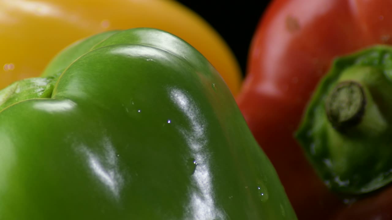 pimientos naturales verduras amarillas, rojas y verdes girando sobre un fondo negro