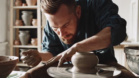 man shaping clay on a pottery wheel in a workshop