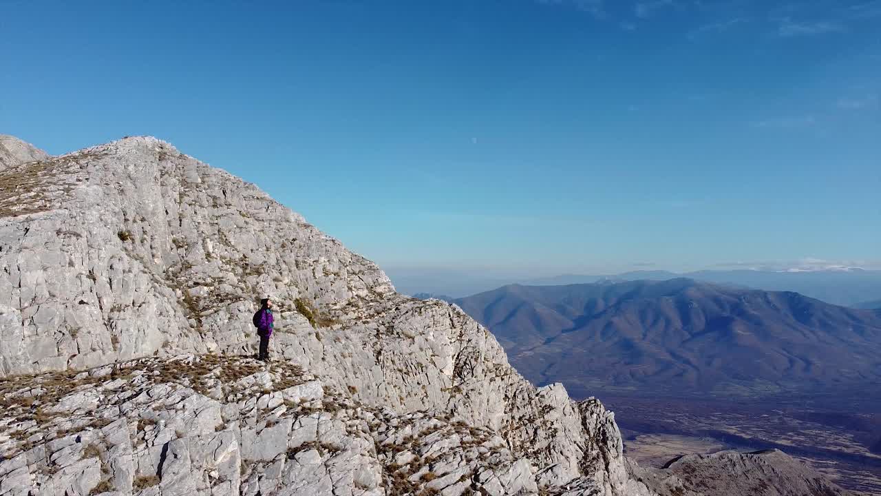 excursionista de pie en un pico de montaña disparado por un dron