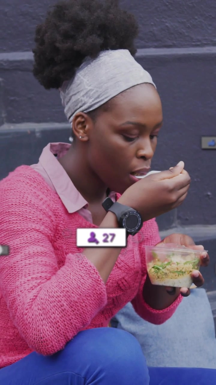 Video verticale: Donna che solleva una forchetta, mangia sui gradini, sovrapposizioni che mostrano contatori per il contenuto alimentare.