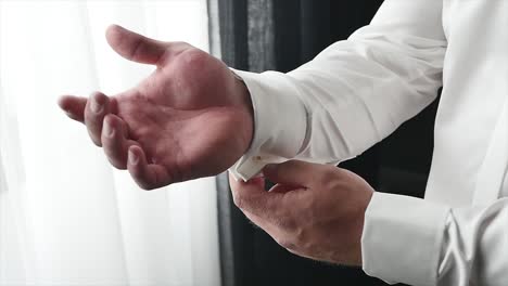 the groom wears a tie and cufflinks boutonniere