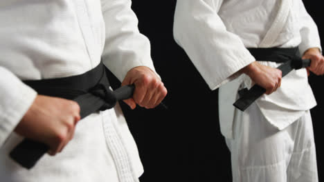 men in black belt standing against black background