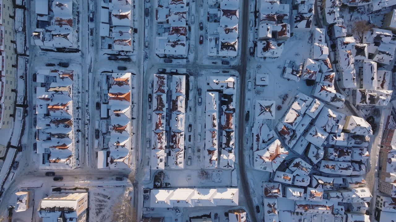 Aerial top-down shot of snow-filled streets and snowy roofs in Bergen, Norway on a sunny winter day