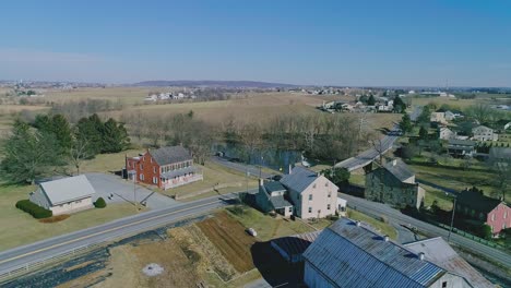 una vista de avión no tripulado del campo amish, con un arroyo, cascada, molino y granjas en invierno