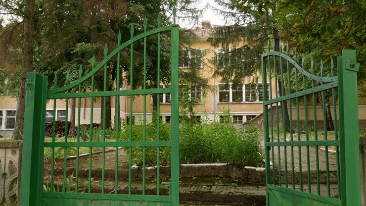 Green painted gates to dated Eastern European education school building