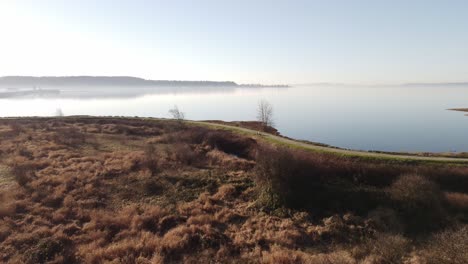 Drone-flying-low-over-the-shore-toward-a-lake