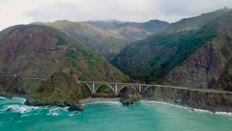 aerial shot of a car driving over bixby creek bridge in big sur on state route 1 in california