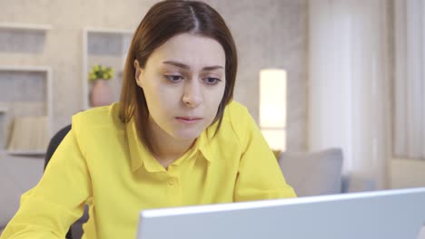 Worried-and-stressed-Focused-young-woman-sitting-at-table-looking-at-laptop.