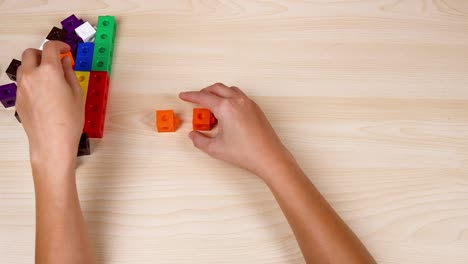 hands assembling colorful linking cubes on table