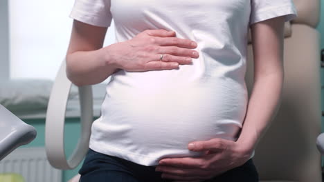 Camera-Focuses-On-Pregnant-Woman's-Hands-Touching-Her-Belly-In-The-Medical-Consultation-1