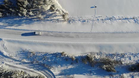 winter landscape with a vehicle driving on snow covered road near lapland, finland - aerial, top down