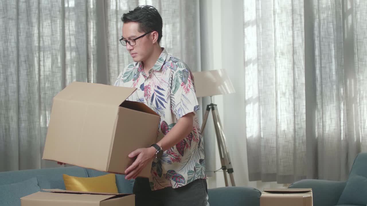 Happy Asian Man Dancing And Celebrating Finish Carrying Cardboard Box With Stuff Into A New House. He Celebrates Moving Day