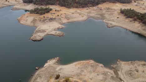 panning areal drone footage looking down at the folsom lake in northern california, water surrounded by dry grass and trees