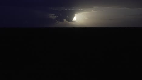 sun or moon in dark sky, illuminating a vast, empty landscape at dusk. clouds gather ominously, showcasing nature's power in a dramatic display.