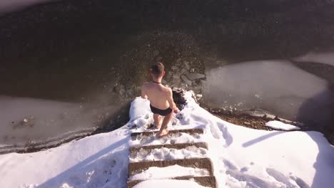 man about to enter frozen lake slips on slick snow covered steps