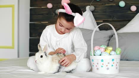 child and her rabbit celebrating easter in bed