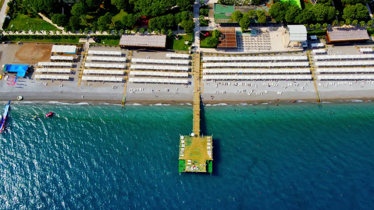 drone aéreo 4k de arriba hacia abajo video de un muelle de madera cerca de un hotel en la ciudad de kiriş - kemer